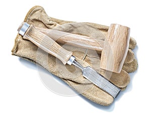 Wooden mallet and chisel on leather gloves isolated white