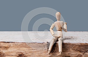 Wooden man dummy sits and speaks on a gray background. Place for text