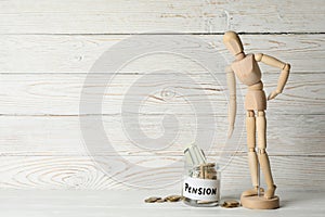 Wooden man and jar with money on wooden background