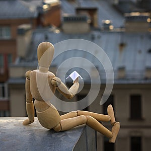 Wooden man launches a paper airplane from the roof in a big industrial city