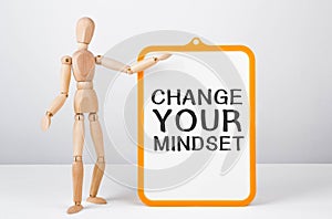 Wooden man shows with a hand to white board with text Change your mindset