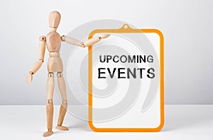 Wooden man shows with a hand to white board with text UPCOMING EVENTS