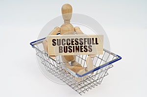 A wooden man sits in a shopping basket, holding a sign in his hands - Successfull Business