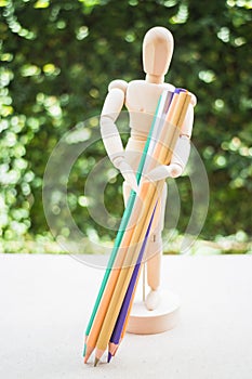 Wooden manikin carrying colour pencil on artist work table