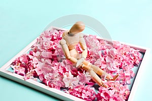 Wooden mannequin on a background of flowers