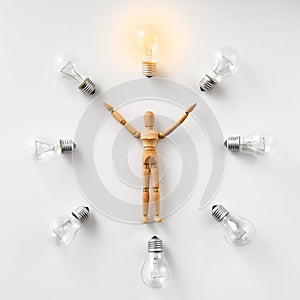 Wooden mannequin carrying glowing light bulb on white