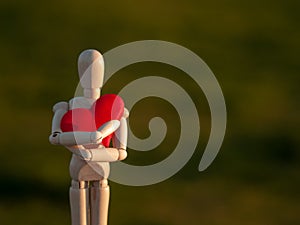 Wooden mannequin embracing his heart with his his hands Concept of romanticism and love photo