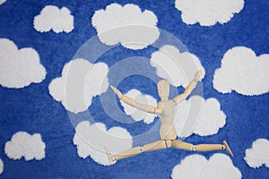 Wooden mannequin happy jump on blue cloudy background