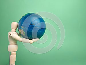 Wooden mannequin holding an earth globe isolated on a green background