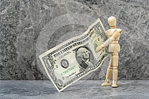 Wooden mannequin holding one dollar banknote