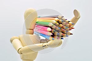 Wooden mannequin loaded with colored pencils photo