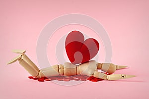 Wooden mannequin lying under heavy heart - Concept of love troubles