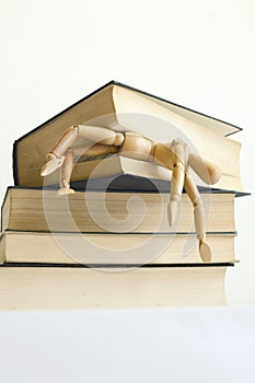 Wooden mannequin manikin student fell under pressure and was killed, crush studying and learning by bunch of books.