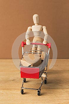 Wooden mannequin with miniature shopping cart photo