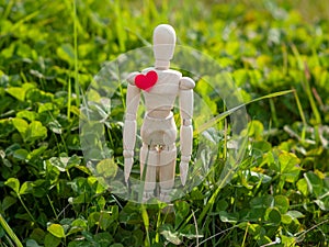 Wooden mannequin with a red heart on his chest. Concept of romanticism and love