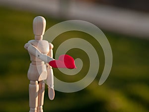 Wooden mannequin with a red heart on his hands Concept of romanticism and love photo