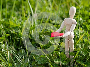 Wooden mannequin with a red heart on his hands in the grass. Concept of romanticism and love photo