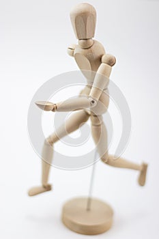 A wooden mannequin running and looking at us.