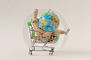 Wooden mannequin in shopping cart with earth globe - Concept of planet earth protection, globalization and economy