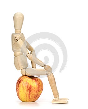 Wooden mannequin sitting on an apple!