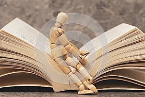 Wooden mannequin sitting on the open book