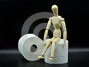 Wooden mannequin sitting on a roll of toilet paper photo