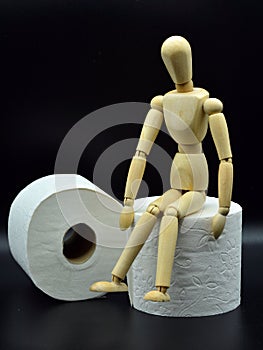 Wooden mannequin sitting on a roll of toilet paper photo