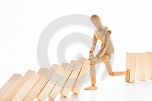 Wooden mannequin stopping domino effect on white