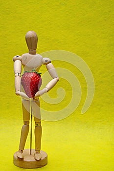 A wooden mannequin with a strawberry