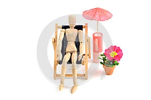 Wooden mannequin taking sunbath in deck chair