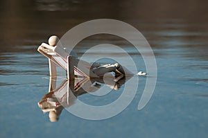 Wooden mannequin in wooden lounge chair in the water