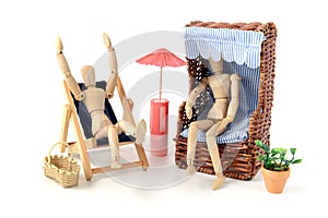 Wooden mannequins sunbathing in garden with chair