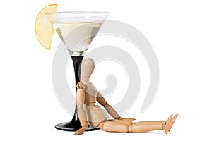 Wooden mannikin sitting near glass of vermouth. Concept of drunkenness, alcohol abuse. photo