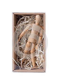 Wooden mannikin standing in closed cardboard box filled with wood shred. Concept of loneliness, isolation, unfreedom.