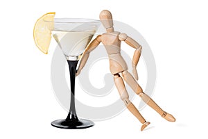 Wooden mannikin standing near glass of vermouth. Concept of drunkenness, alcohol abuse photo