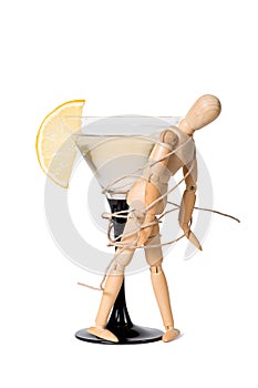 Wooden mannikin strapped to the glass of vermouth. Concept of drunkenness, alcohol abuse