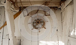 A wooden marine steering wheel hangs on the wall as a decorative element