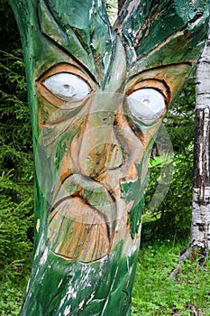 Wooden mask on tree trunk. Closeup view