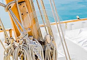 Yachting, rigging nautical ropes tied on wood mast on deck of classical sailing boat