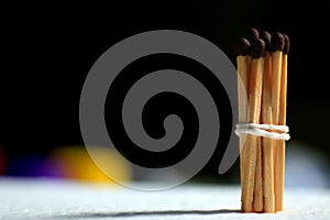 Wooden matches tied in rubber band rope on black background. Freedom and togetherness concept with copy space for text design.