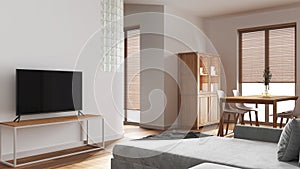 Wooden minimal dining and living room in white tones. Velvet sofa, table with chairs, glass block wall. Cabinets and tv stand.