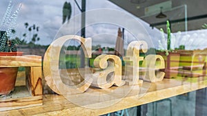 Wooden mockup signboard for cafe behind a large glass window  that reflects the view outside the coffee shop for background