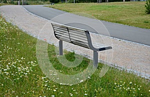 Wooden modern park bench with a metal relief structure on one leg stands in the park in rest areas and on paths made of a small