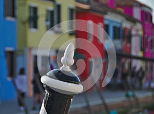 Wooden mooring pole in front of colorful houses in Burano, Italy