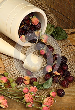 Wooden mortar and scattered rose hips