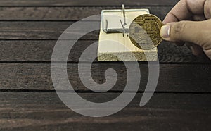 Wooden mouse trap and man holds backside of bitcoin.