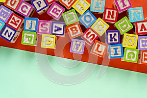 Wooden multicolored blocks with letters on orange background. Education for preschooler, reading, alphabet. Back to school concept
