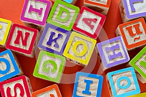 Wooden multicolored blocks with letters on orange background. Education for preschooler, reading, alphabet. Back to school concept
