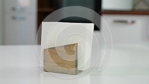Wooden napkin holder with paper serviettes on kitchen table. Space for text