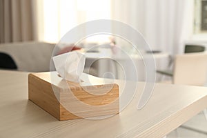 Wooden napkin holder with paper serviettes on table in room.